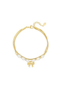 Sierlijke armband platte schakel, parels en strikje goudkleurig